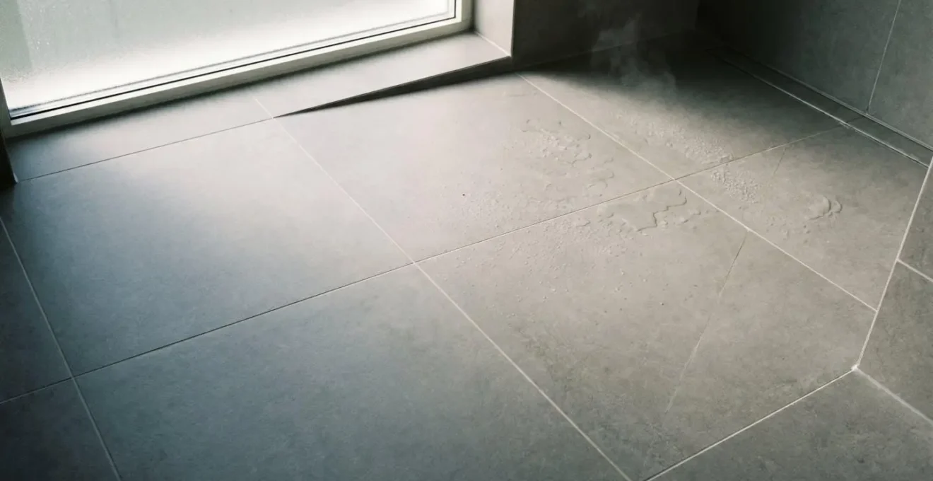 Salle de bain avec grand carrelage en grès cérame gris, joints fins et lumière naturelle tamisée